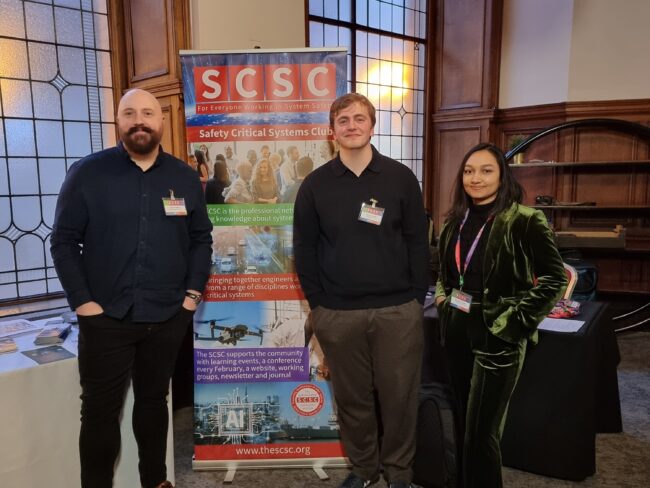 3 PhD researchers stood in front of their conference poster.